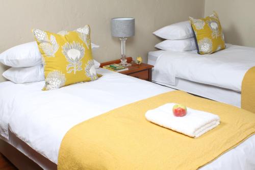 una habitación de hotel con 2 camas y una manzana en una toalla en The Apple Blossom Cottage en Villiersdorp