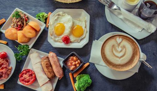a table topped with plates of food and a cup of coffee at Le Petit Village Boutique Hotel & Spa in Kampala