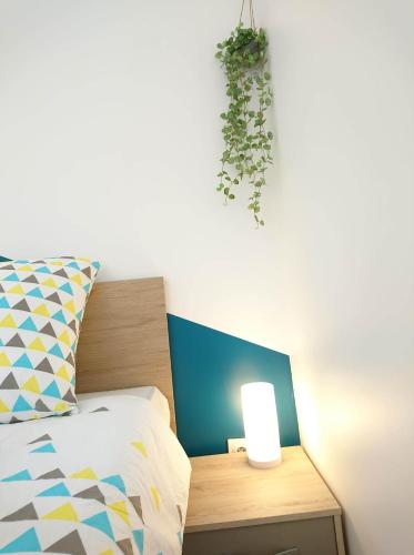 a bed with a light on a night stand next to a bed sidx sidx sidx at LP Appart in Annecy