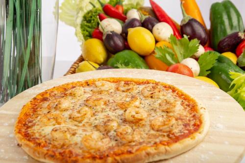 a pizza sitting on a cutting board next to a salad at Holiday Inn Yanbu by IHG in Yanbu