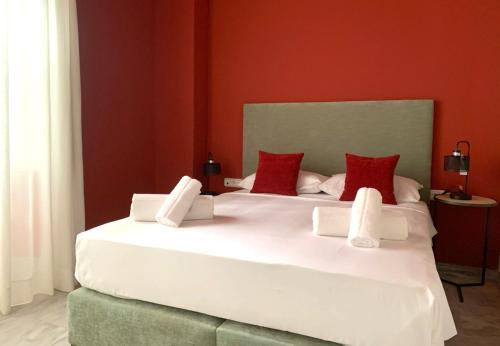a bedroom with a large white bed with red walls at Ritual Sevilla Suites Alameda 1 in Seville