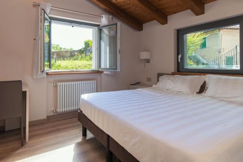 um quarto com uma cama grande e 2 janelas em Er Mirin - Il Mulino di Carcare Hotel em Carcare