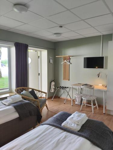 1 dormitorio con 2 camas, mesa y escritorio en Lygnerns pensionat och konferens en Sätila