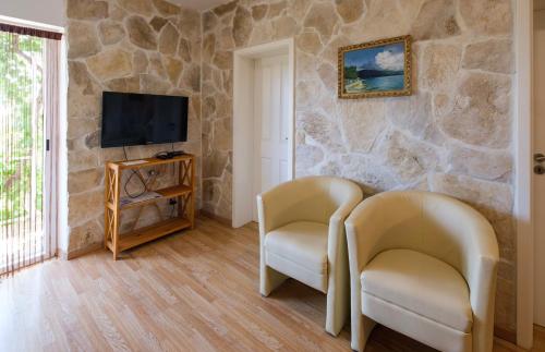 two chairs in a living room with a stone wall at Apartments Kaktus Orebic in Orebić