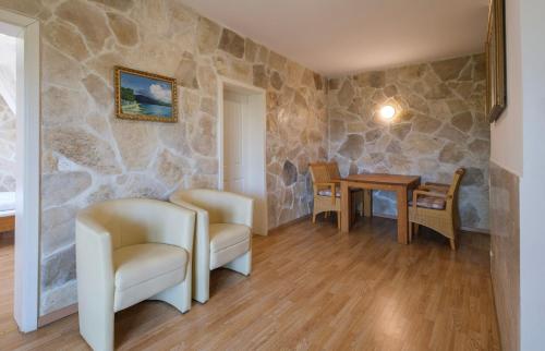 a room with two chairs and a table and a stone wall at Apartments Kaktus Orebic in Orebić
