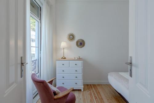 ein Schlafzimmer mit einem Stuhl, einer Kommode und einem Fenster in der Unterkunft Príncipe Real Flamingo Residence in Lissabon