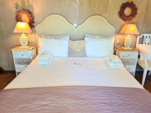 a large white bed with two night stands and two lamps at Villa Vravrona Tower & Suites in Markopoulo