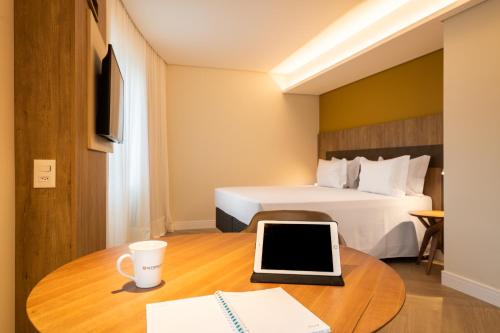 a hotel room with a bed and a desk with a laptop at Intercity Portofino Florianópolis in Florianópolis