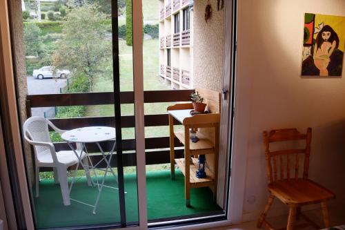een kamer met een balkon met een tafel en een raam bij Triplex Idéal Famille in Cauterets