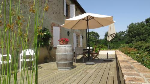 a patio with an umbrella and a table and chairs at Le Mas De Marie in Lavaur