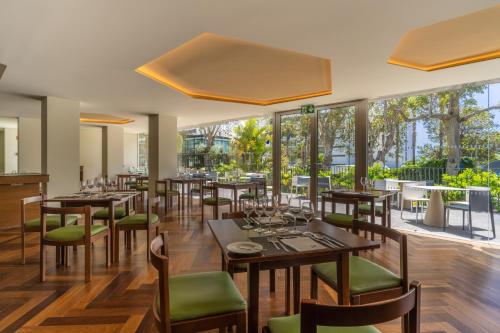 a restaurant with tables and chairs and large windows at Hotel Girassol - Suite Hotel in Funchal