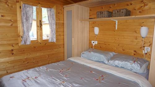 1 dormitorio con 1 cama en una cabaña de madera en VAKANTIEHUIS CASASdeCASPER - Camping Italië, en Porlezza