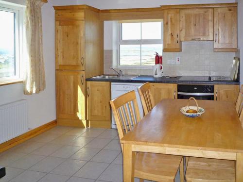 una cocina con armarios de madera y una mesa con un tazón. en Old Barn Holiday Cottage by Trident Holiday Homes, en Skibbereen