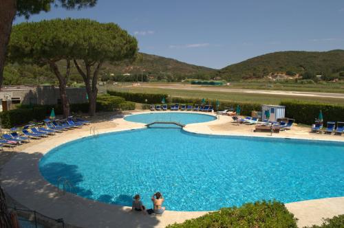 two people sitting in front of a large swimming pool at Aviotel Residence in Marina di Campo
