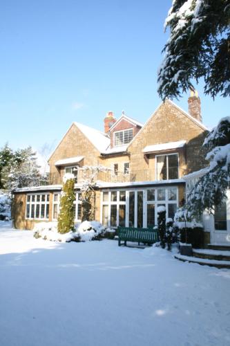 a large house with a bench in the snow at The Grange at Oborne in Sherborne