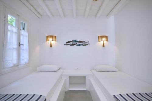 two beds in a room with white walls and lights at Evlalia Studios & Villas in Skopelos Town