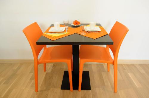 ローマにあるHoney Roomsのテーブル(オレンジの椅子付)、黒いテーブル(食器付)