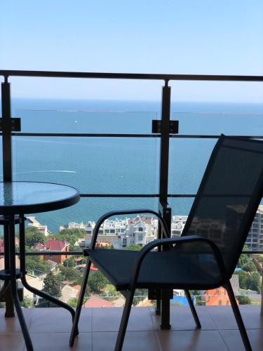 a table and chair on a balcony with a view of the ocean at Arcadia apartment & sea terrace in Odesa