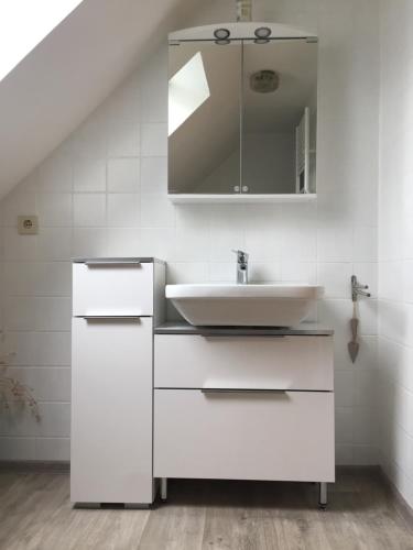 ein weißes Badezimmer mit Waschbecken und Spiegel in der Unterkunft Ferienwohnungen im Gästehaus Sieberns in Carolinensiel