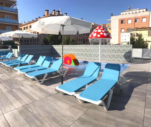 a group of blue lounge chairs and an umbrella at Hotel Maria del Mar in Lloret de Mar