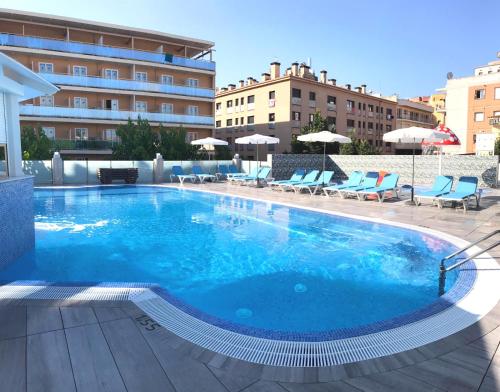 a large swimming pool with chairs and a building at Hotel Maria del Mar in Lloret de Mar