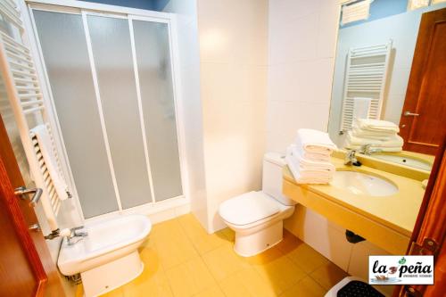 a white bathroom with a toilet and a sink at Apartamentos Turísticos La Peña in Baños de Montemayor