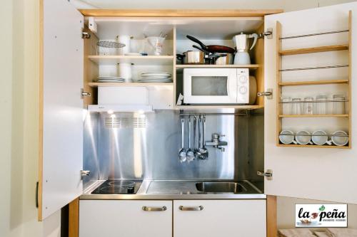 a kitchen with a sink and a microwave at Apartamentos Turísticos La Peña in Baños de Montemayor