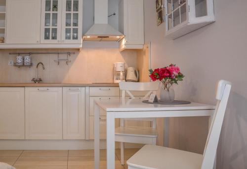 a kitchen with white cabinets and a table with flowers on it at Apartamenty na Wyspie - Feniks - Parking in Świnoujście