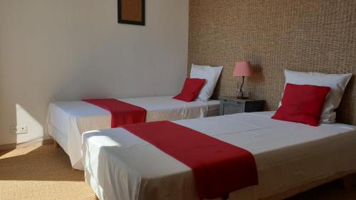 2 camas en una habitación de hotel con sábanas rojas y blancas en De passage chez Lili, en Poligny