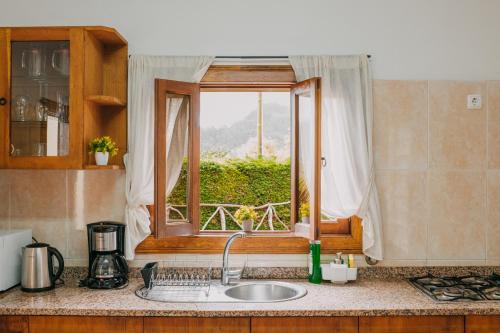 Casa do Faial في سانتانا: طاولة مطبخ مع حوض ونافذة