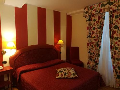 a hotel room with a bed with a red bedspread at Hotel La Luna in Lucca