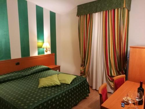 a bedroom with a green bed and a table at Hotel La Luna in Lucca