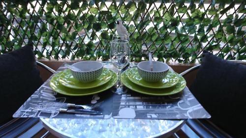 - une table avec des assiettes vertes et un verre de vin dans l'établissement Nicolas 2, à Cannes