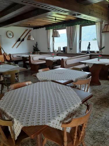 une salle à manger avec des tables et des chaises ainsi qu'une grande fenêtre dans l'établissement Fruhstuckspension Bischof i d Wiesen, à Sankt Peter am Kammersberg