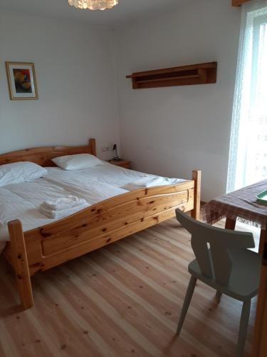 a bedroom with a wooden bed with a desk and a chair at Fruhstuckspension Bischof i d Wiesen in Sankt Peter am Kammersberg