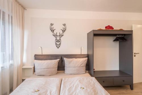 シェーンヴァルトにあるHeimelig im Hirschen App 118のベッドルーム1室(鹿の頭が壁に掛けられたベッド1台付)