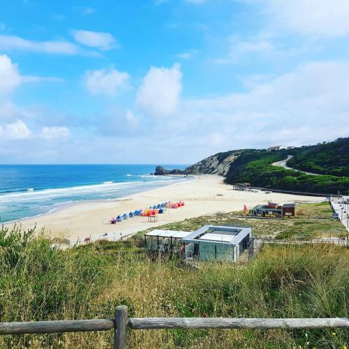 a sandy beach with umbrellas and the ocean at Paredes da Vitória in Senhora da Vitória