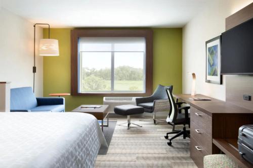a hotel room with a bed and a desk and chairs at Holiday Inn Express Stuart, an IHG Hotel in Stuart