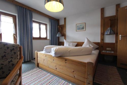 a bedroom with a large bed with white sheets at Gästehaus Inzeller Hof in Inzell