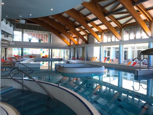 a swimming pool with tables and chairs in a building at Relax and Spa - DeLux Apartman in Velence
