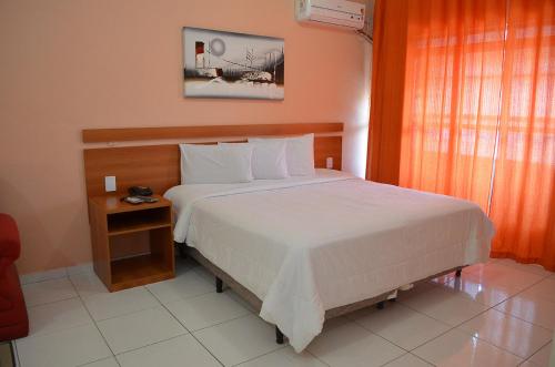 Un dormitorio con una gran cama blanca y una mesa en Calabreza Hotel e Restaurante - By UP Hotel, en Três Corações