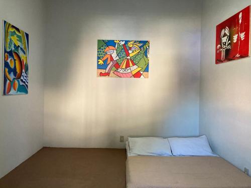 Habitación con cama y pinturas en la pared. en Zizi Home en Chapada dos Guimarães