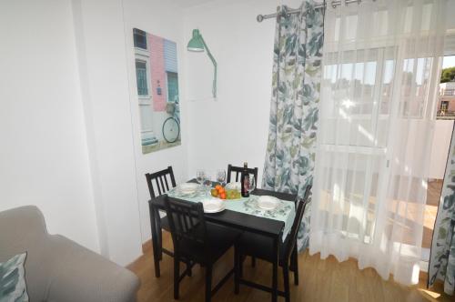 a small dining room table with two chairs and a window at ATICO LA ILUSION CON PARkING in Sanlúcar de Barrameda