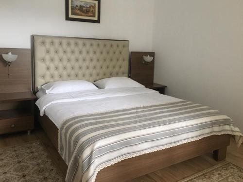 a bedroom with a large bed with white sheets and pillows at Pensiunea Encian in Colibiţa