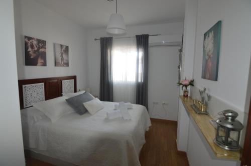 a bedroom with a white bed and a window at ATICO LA ILUSION CON PARkING in Sanlúcar de Barrameda