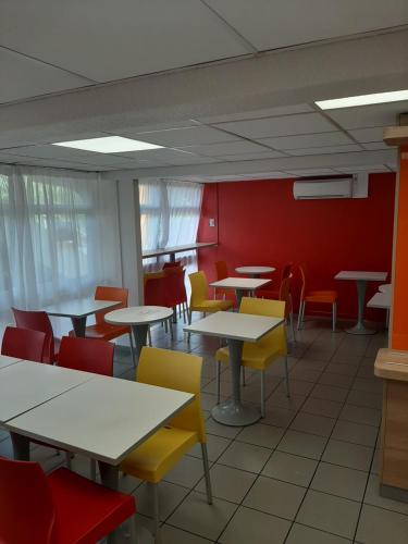 a dining room with tables and colorful chairs at Premiere Classe Carcassonne in Carcassonne