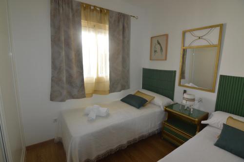 a bedroom with two twin beds and a mirror at ATICO LA ILUSION CON PARkING in Sanlúcar de Barrameda