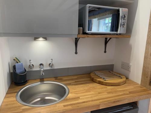 a kitchen with a sink and a microwave at Newton Farmhouse in Whiteparish