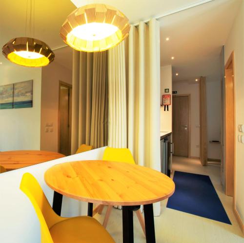 a dining room with a wooden table and yellow chairs at Almar Apartments in Póvoa de Varzim