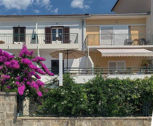 een gebouw met een paraplu en paarse bloemen bij BEACH APARTMENT in Podgora